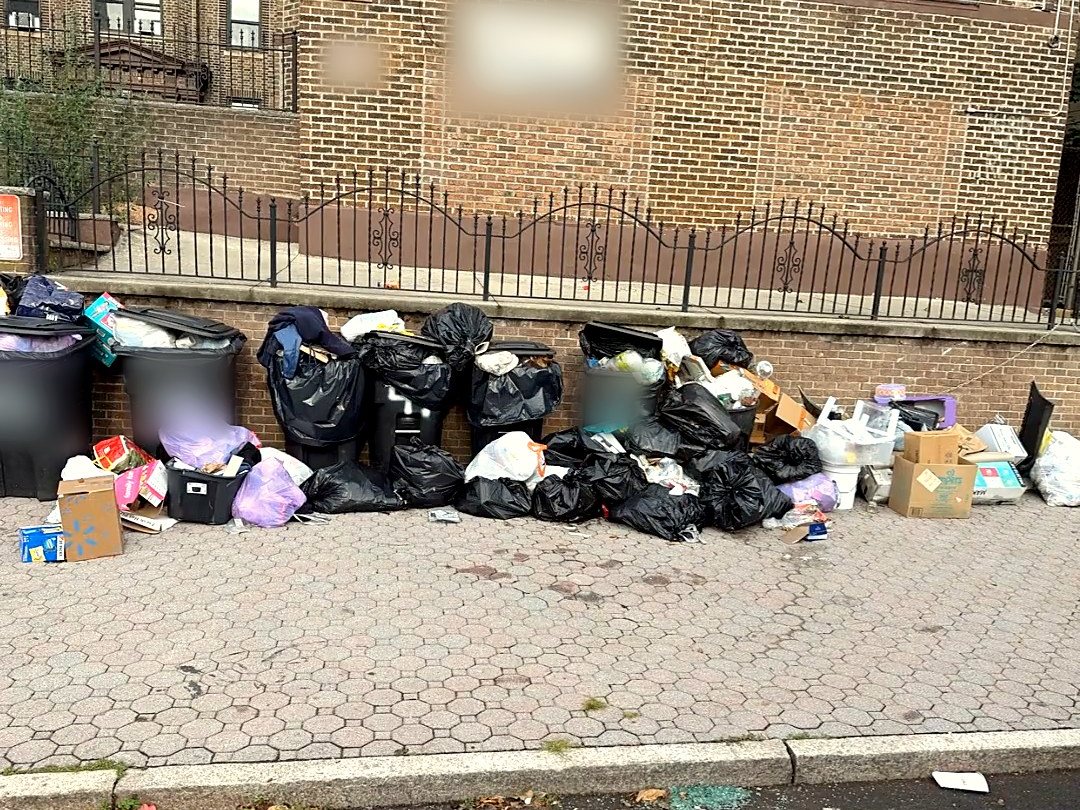 Before: bags, overflowing bins, and boxes piled along the building's whole wall.